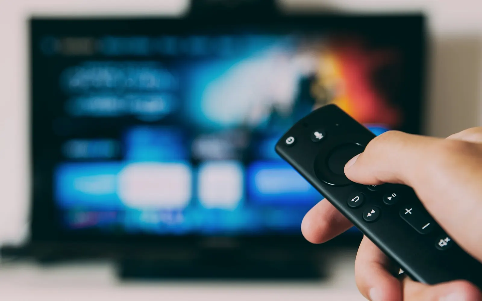 Remote control pointed at a blurred smart TV streaming interface